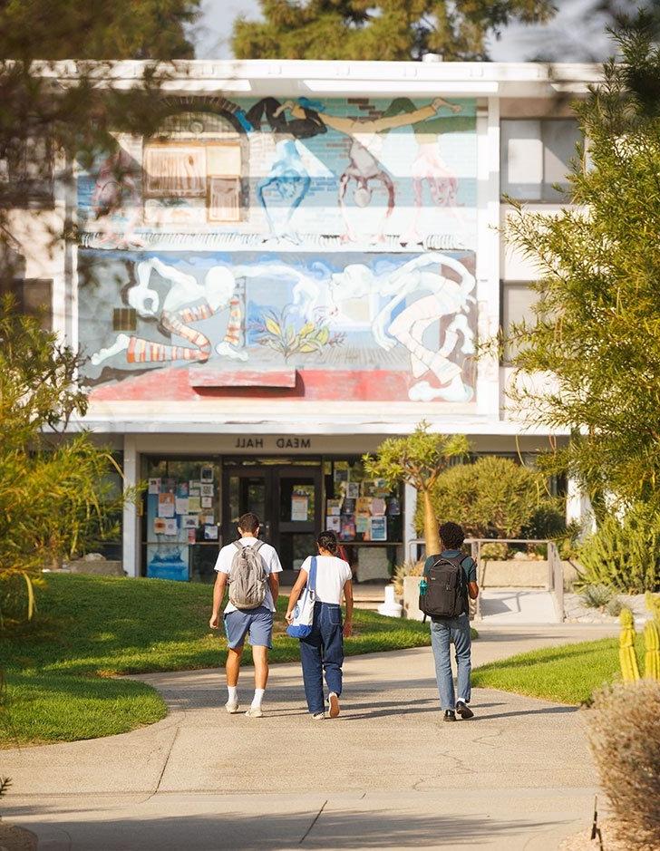 three students walk toward the entrance of mead hall